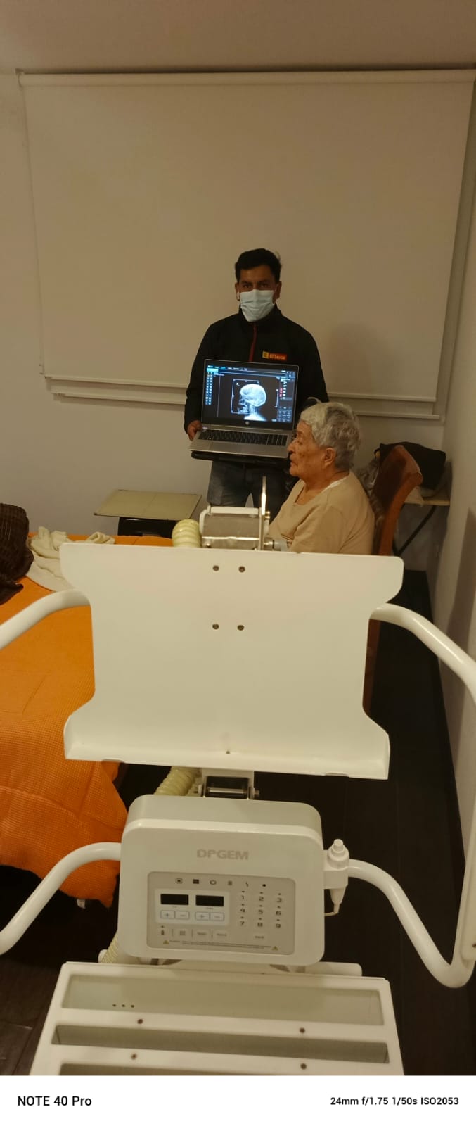 Tecnólogo revisando radiografía de cráneo con paciente adulto mayor sentado